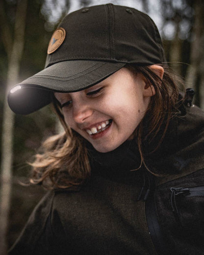 Pine Green coloured Seeland Childrens Skarn LED Junior Cap on forest background #colour_pine-green