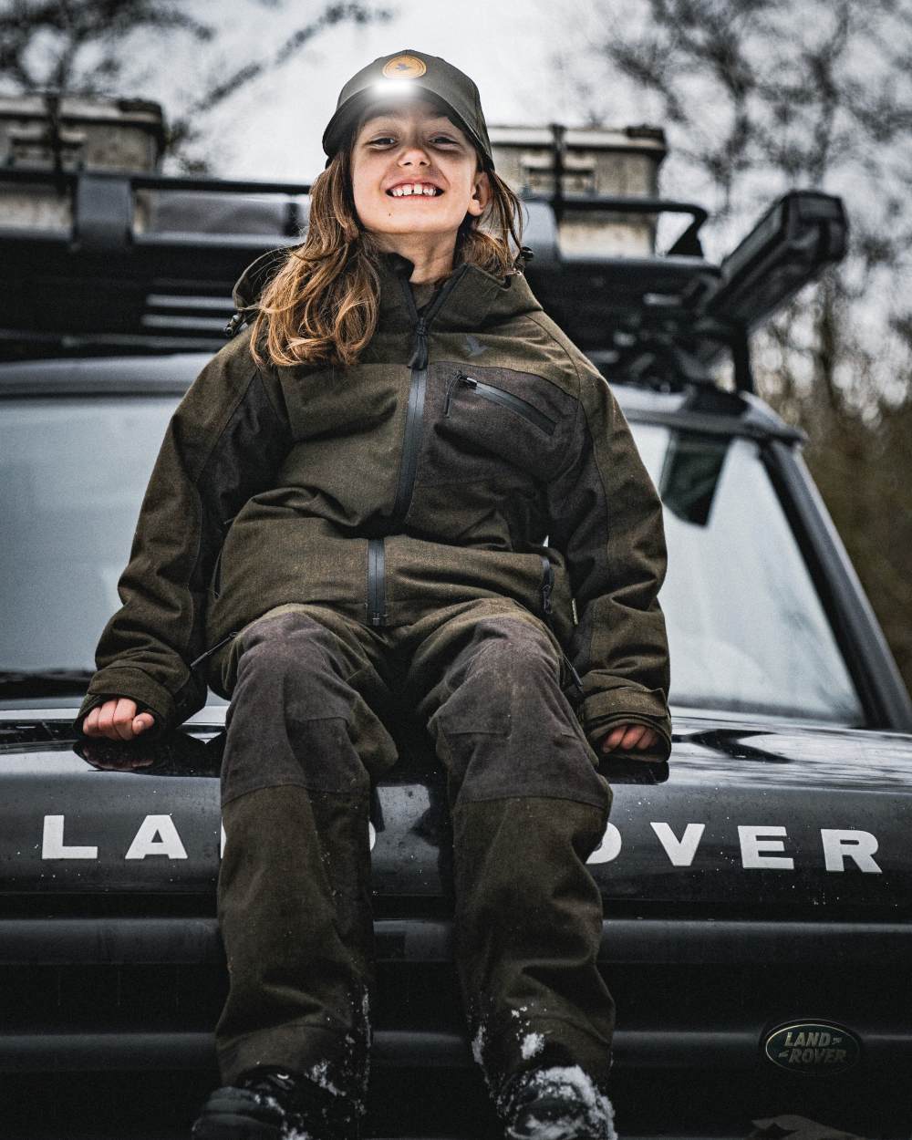 Pine Green coloured Seeland Childrens Skarn LED Junior Cap on forest background #colour_pine-green