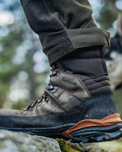 Dark Brown coloured Seeland Enduro Tracker High Boots on forest background #colour_dark-brown
