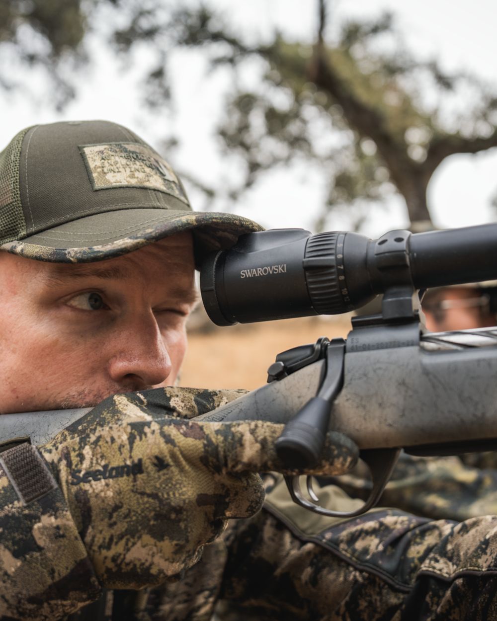 InVis MPC Green coloured Seeland Grip Camo Gloves on forest background #colour_invis-mpc-green