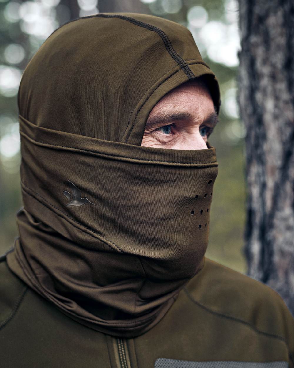 Pine Green Coloured Seeland Hawker Scent Control Balaclava on forest background #colour_pine-green