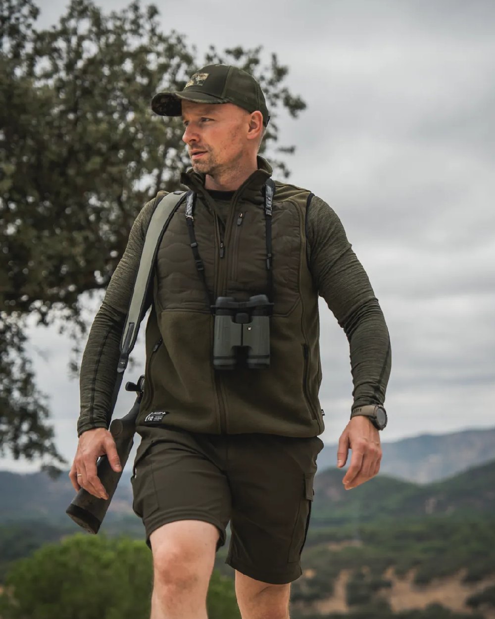 Pine Green Coloured Seeland Mens Gale Fleece Waistcoat on forest background #colour_pine-green
