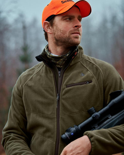 Pine Green InVis Orange Blaze Coloured Seeland Vantage Reversible Fleece Jacket on forest background #colour_pine-green-invis-orange-blaze