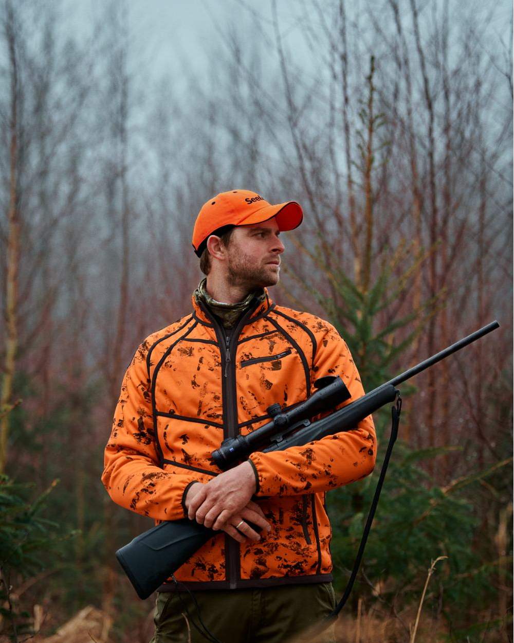 Pine Green InVis Orange Blaze Coloured Seeland Vantage Reversible Fleece Jacket on forest background #colour_pine-green-invis-orange-blaze