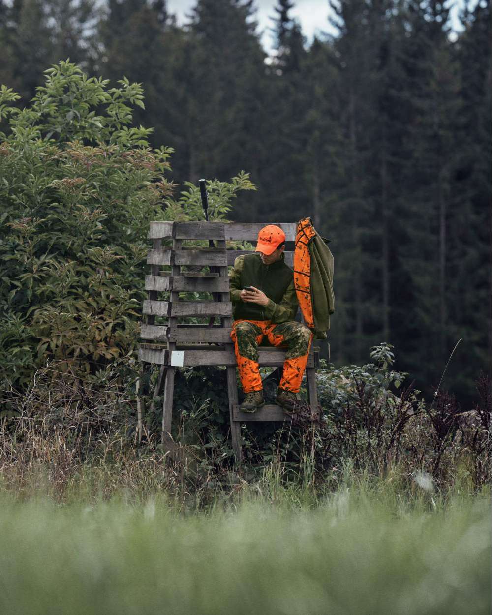 InVis Green InVis Orange Blaze Coloured Seeland Vantage Trousers on forest background #colour_invis-green-invis-orange-blaze
