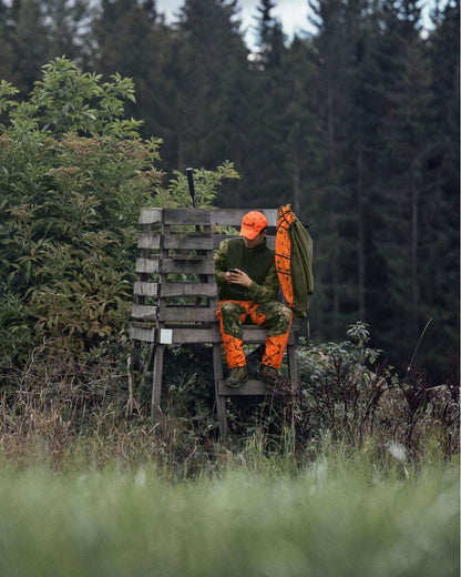 InVis Green InVis Orange Blaze Coloured Seeland Vantage Trousers on forest background #colour_invis-green-invis-orange-blaze