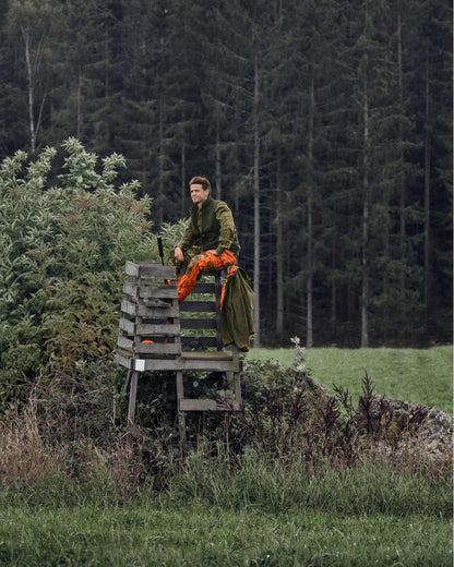 InVis Green InVis Orange Blaze Coloured Seeland Vantage Trousers on forest background #colour_invis-green-invis-orange-blaze