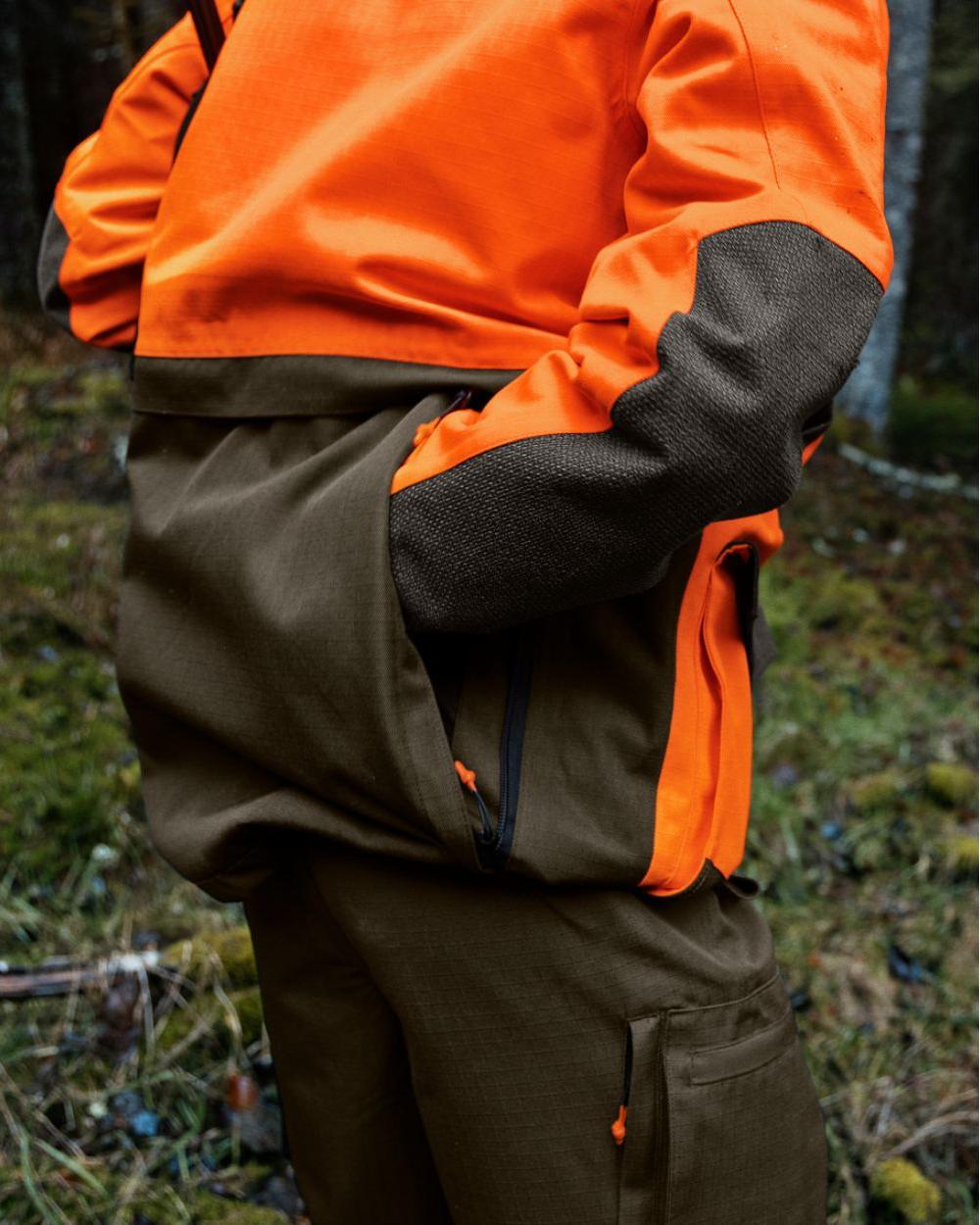 Pine Green Hi-Vis Orange Coloured Seeland Venture Rover Jacket on forest background #colour_pine-green-hi-vis-orange