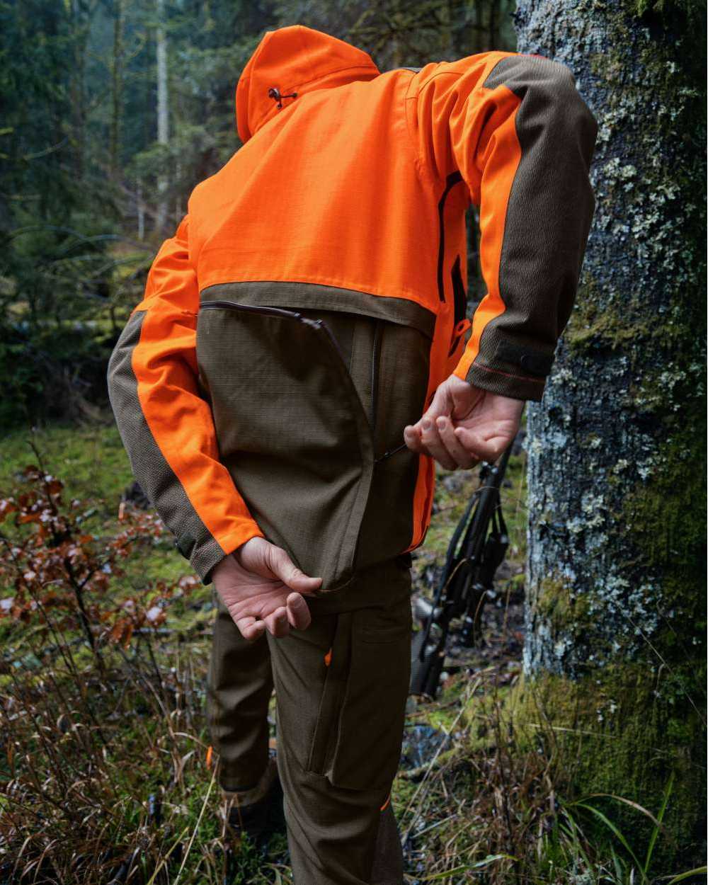 Pine Green Hi-Vis Orange Coloured Seeland Venture Rover Jacket on forest background #colour_pine-green-hi-vis-orange