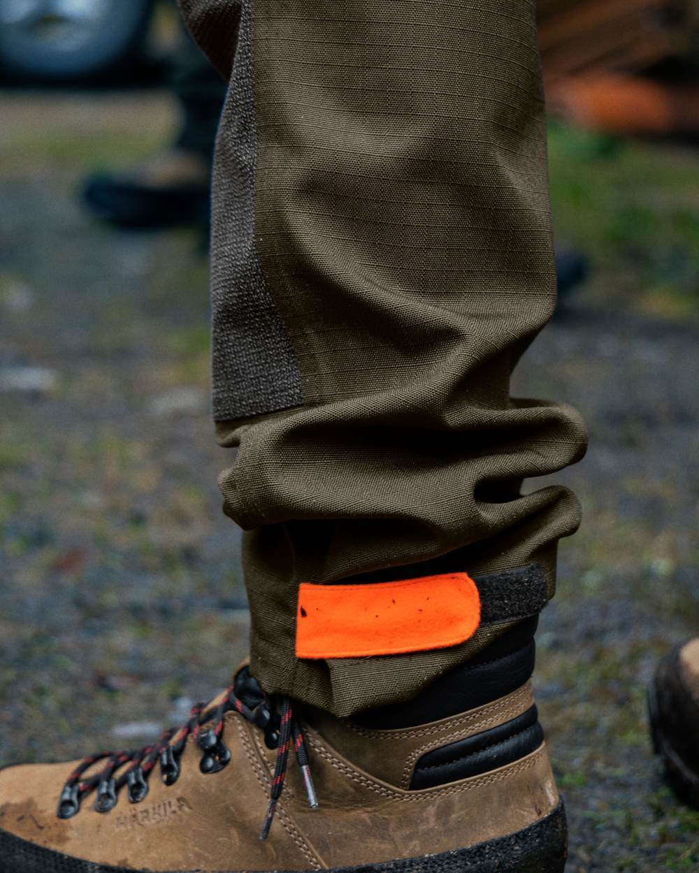 Pine Green Hi-Vis Orange Coloured Seeland Venture Trousers on forest background #colour_pine-green-hi-vis-orange