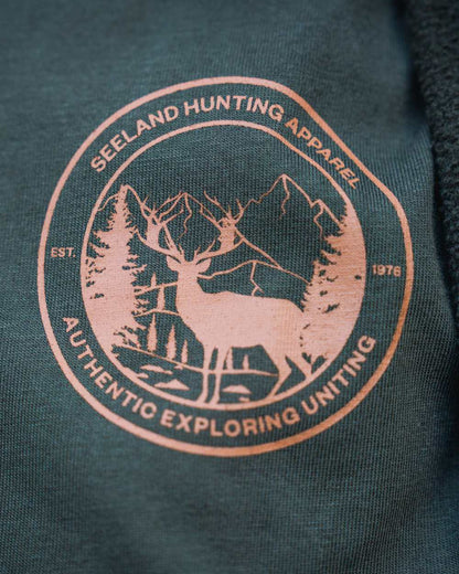 Pine Green Coloured Seeland Womens Hunting Heritage T-Shirt on forest background #colour_pine-green
