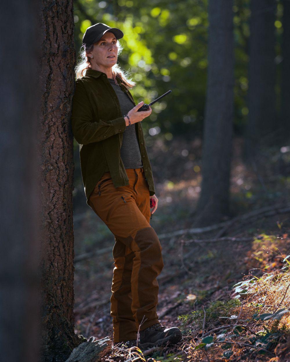 Burnt Clay coloured Seeland Womens Larch Membrane Trousers on forest background #colour_burnt-clay