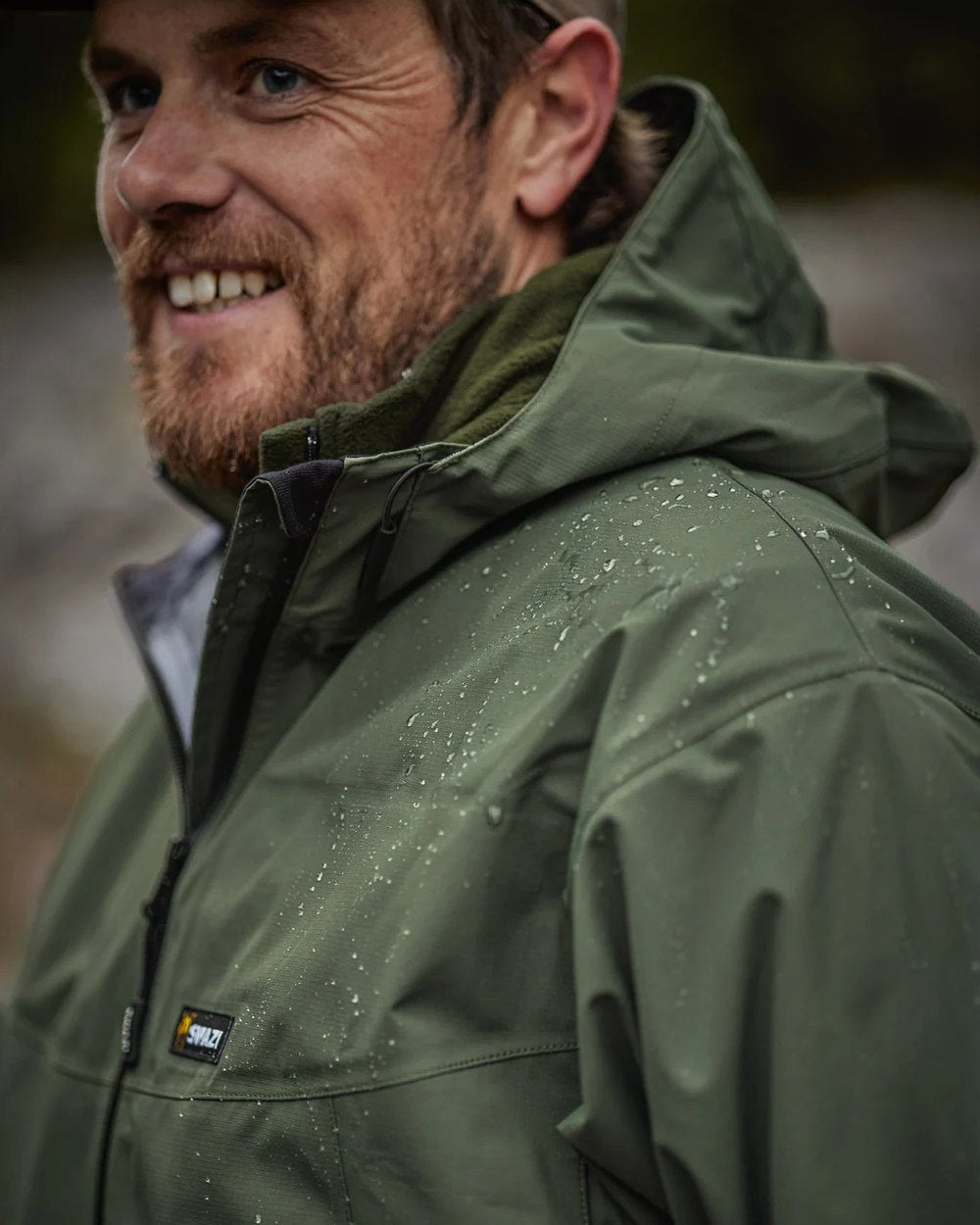 Olive coloured Swazi Mens Sentinel Ultralight Jacket on rock background #colour_olive