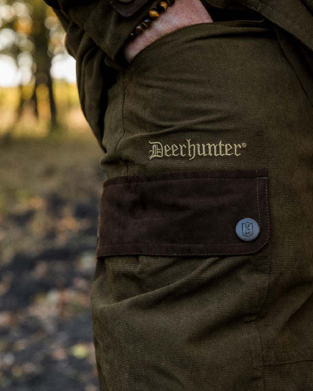 Tarmac Green coloured Deerhunter Eagle Trouser on a blurry background #colour_tarmac-green
