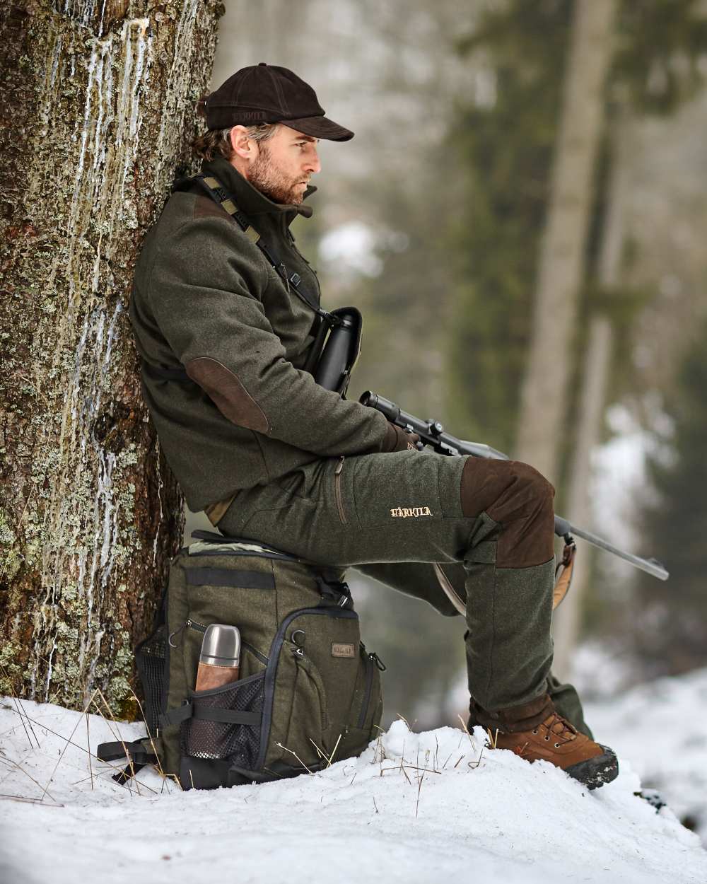 Hunting Green Coloured Harkila Metso Rucksack Chair Backpack on snow background #colour_hunting-green