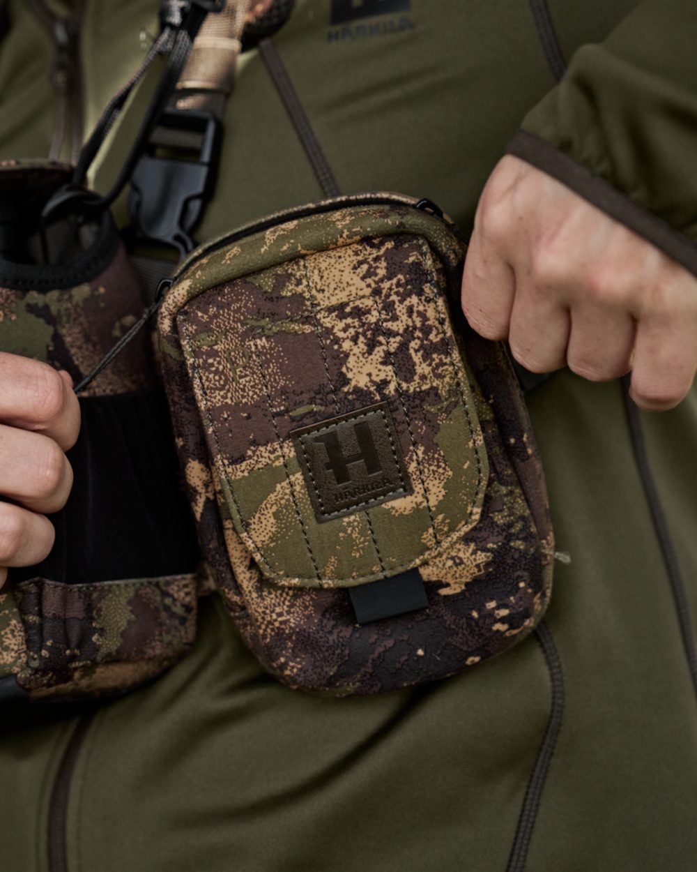 AXIS MSPForest Coloured Harkila Utility Camo Pouch on blurry background #colour_axis-mspforest