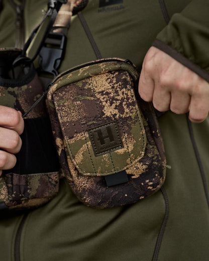 AXIS MSPForest Coloured Harkila Utility Camo Pouch on blurry background #colour_axis-mspforest