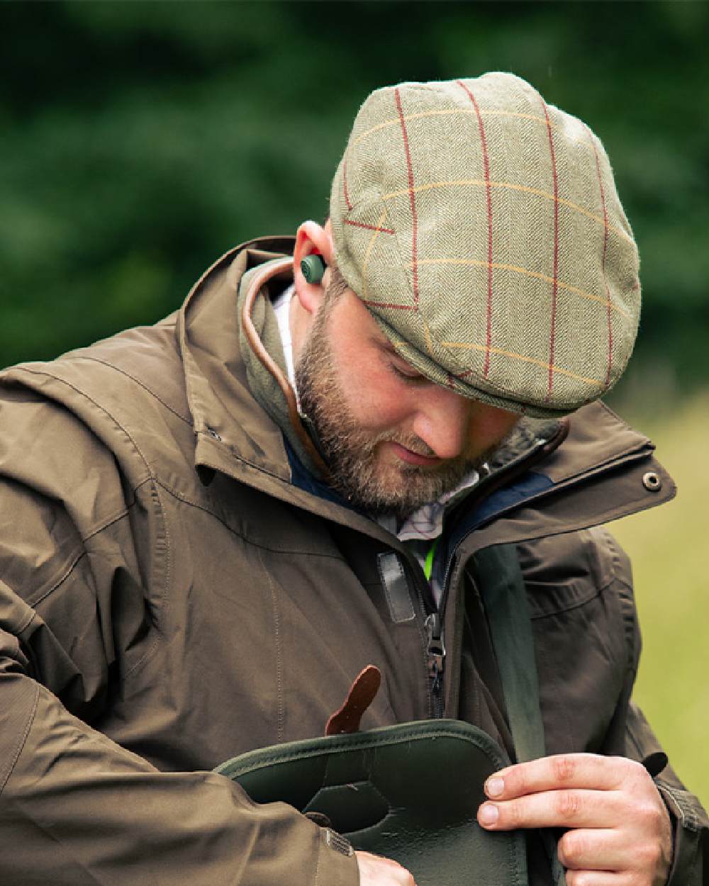 Tweed Green Coloured Jack Pyke Wool Blend Tweed Flat Cap On A Blurry Background #colour_tweed-green