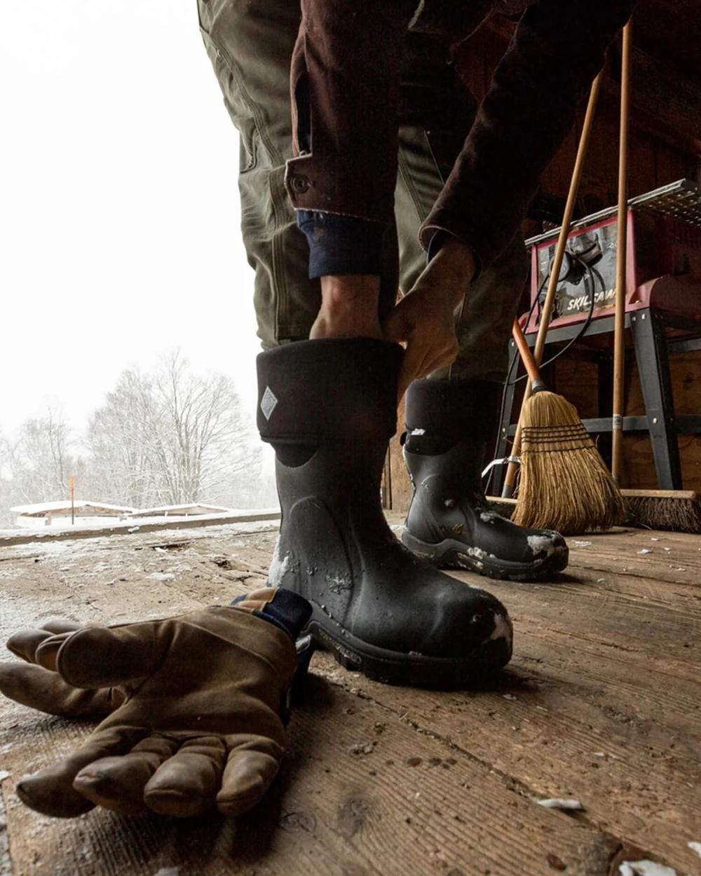 Black Coloured Muck Boots Arctic Sport Tall Wellingtons On A Shelter Background #colour_black