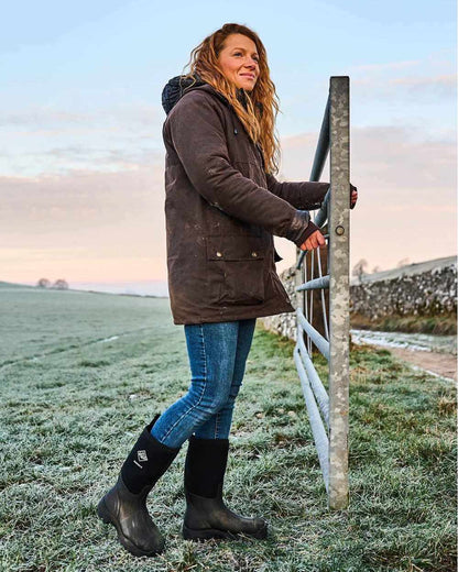 Black Coloured Muck Boots Derwent II Wellingtons On A Field Background #colour_black