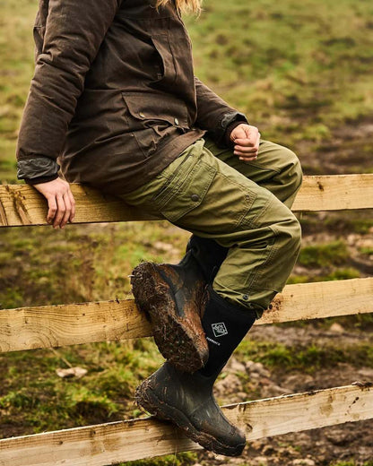 Black Coloured Muck Boots Derwent II Wellingtons On A Forest Background #colour_black