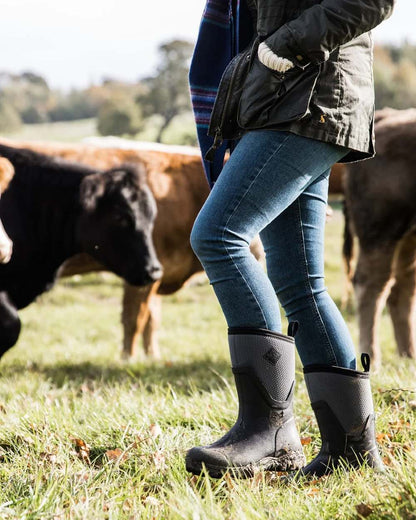Black Grey Coloured Muck Boots Womens Arctic Sport II Mid Wellingtons On A Field Background #colour_black-grey