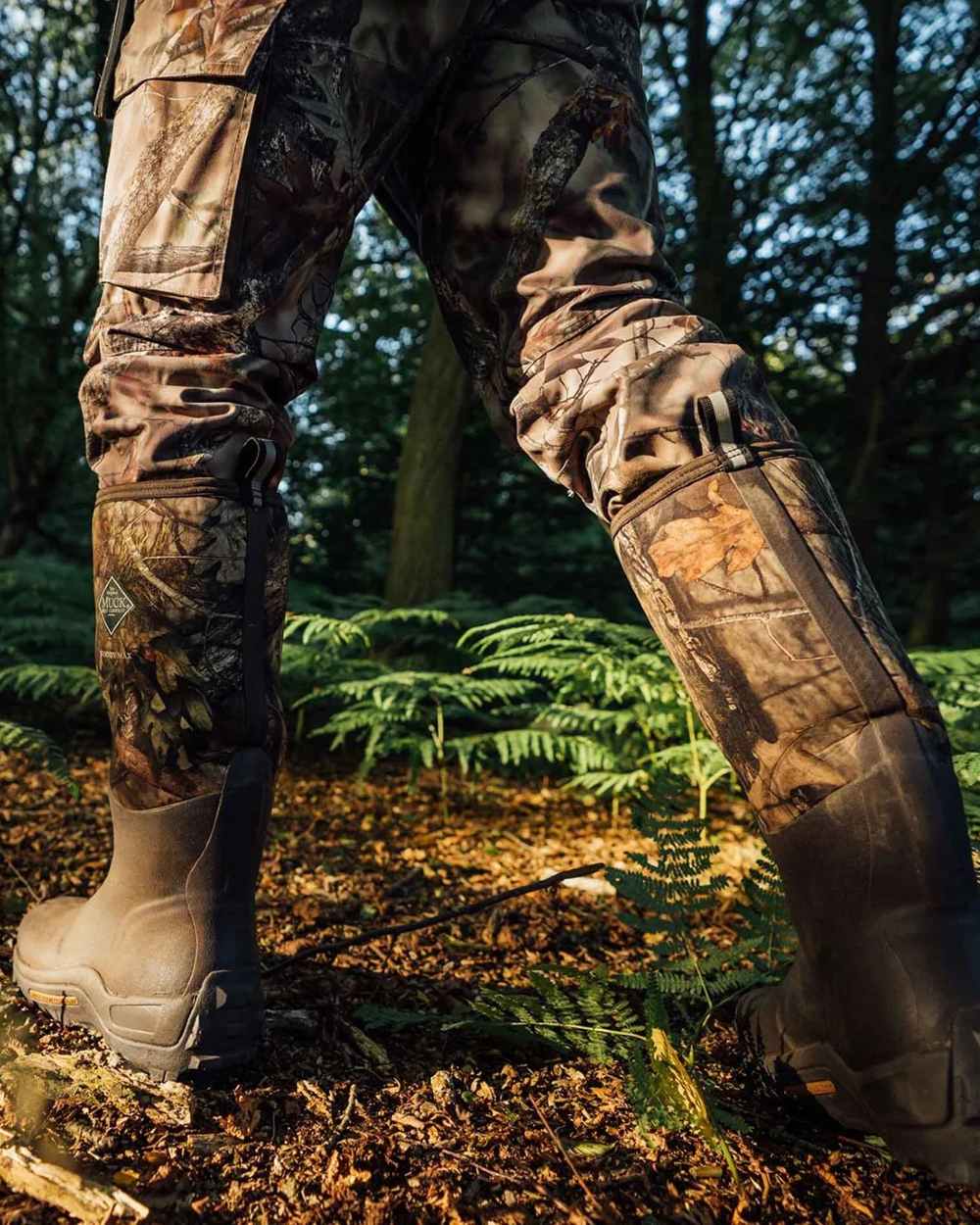 Mossy Oak Infinity Print Coloured Muck Boots Woody Max Tall Wellingtons On A Forest Background #colour_mossy-oak-infinity-print